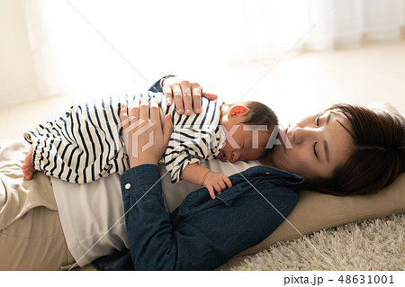 赤ちゃんをラッコ抱きで寝かしつける母親 子育て 育児の写真素材