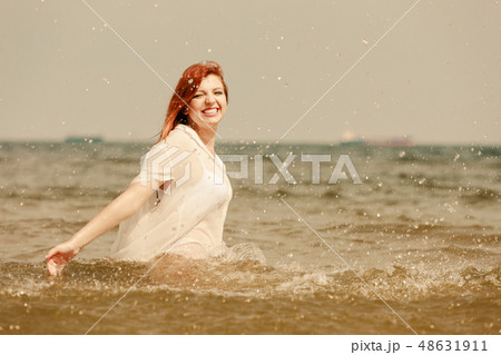 Redhead woman playing in water during summertime 48631911
