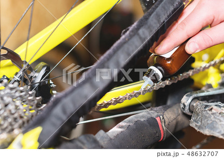 Close-up of a man's hand, led by masters, lubricate the bicycle chain of a mountain bike with a 48632707