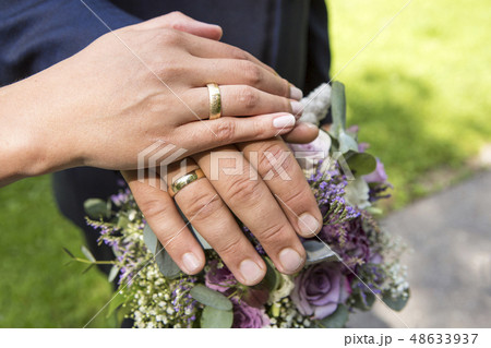 Hands of bride and groom with flower bouquet Hands of bride and groom with flower bouquet 48633937