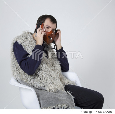 young man with a mask on his face sits in a white young man with a mask on his face sits in a white 48637280