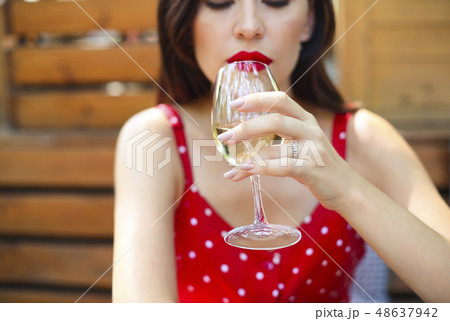 Woman wearing polka dots dress having wine in a Woman wearing polka dots dress having wine in a 48637942