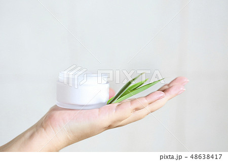 Woman holding cream with green bamboo leaves in 48638417