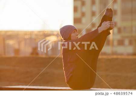 A girl in sports clothes doing a boat pose 48639574