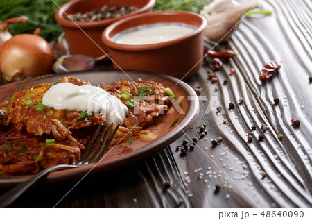 Homemade tasty potato pancakes in clay dish 48640090