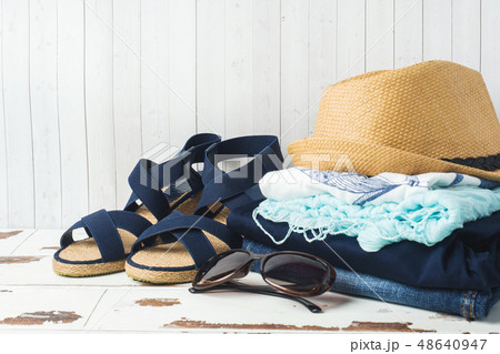 A stack of women's clothing and a straw hat  48640947