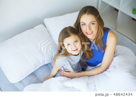Young woman playing with little girl on bed 48642434
