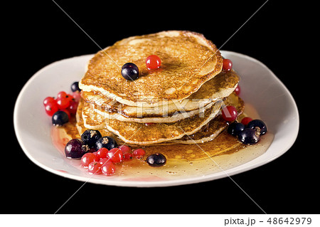 Pancakes with honey and currant. Black background. Selective focus. Pancakes with honey and currant. Black background. Selective focus. 48642979