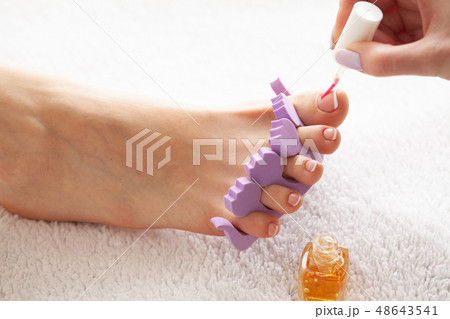 Hand and Nail Care. Beautiful Women's Feet with Pedicure in Beauty Salon. The Master Applying on 48643541
