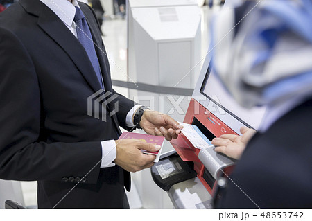 空港で自動チェックイン機の使い方を教わるビジネスマン手元 48653742