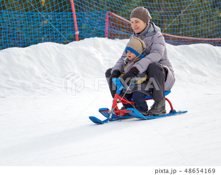 Happy mom with son rides a sled from mountain 48654169