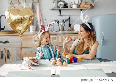 Mother with little daughter in a kitchen Mother with little daughter in a kitchen 48654315