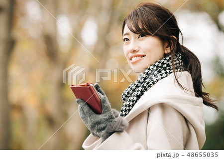 コートを着た若い日本人女性　冬　スマホ　公園 48655035