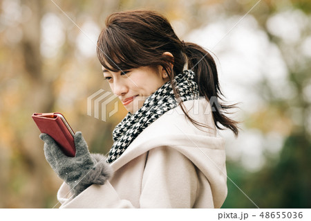 コートを着た若い日本人女性　冬　スマホ　公園 48655036