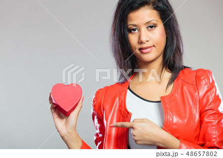 Girl in red holding heart gift Girl in red holding heart gift 48657802