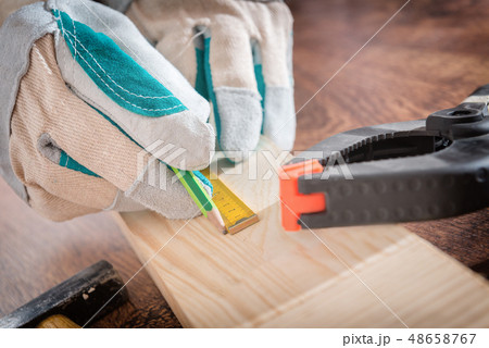 Carpenter measuring a wooden plank 48658767