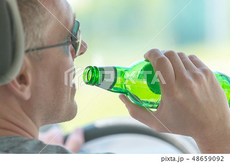 Man drinking beer while driving a car Man drinking beer while driving a car 48659092