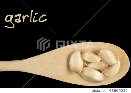 garlic clove on wooden spoon isolated on black garlic clove on wooden spoon isolated on black 48660032
