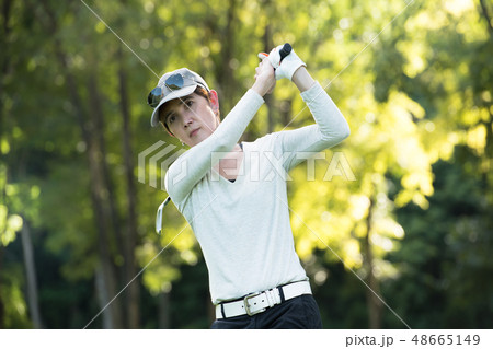 Asian woman playing golf on natural golf course Asian woman playing golf on natural golf course 48665149