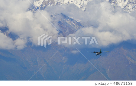 A passenger airplane flying over the mountains 48671158