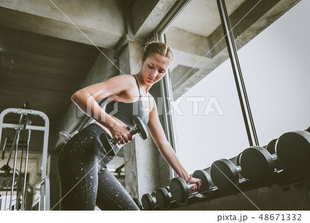woman working out at gym doing dumbbell row 48671332