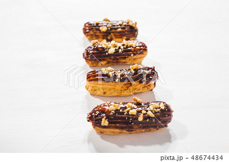 Food, bakery and desserts concept - row of eclairs on white background Food, bakery and desserts concept - row of eclairs on white background 48674434