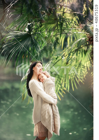 Young and happy mother cares for her young son, and walks along the shore of the lake in the summer 48675319