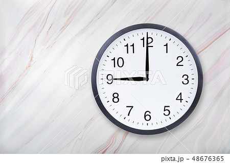 Wall clock show nine o'clock on marble texture. Office clock show 9pm or 9am Wall clock show nine o'clock on marble texture. Office clock show 9pm or 9am 48676365