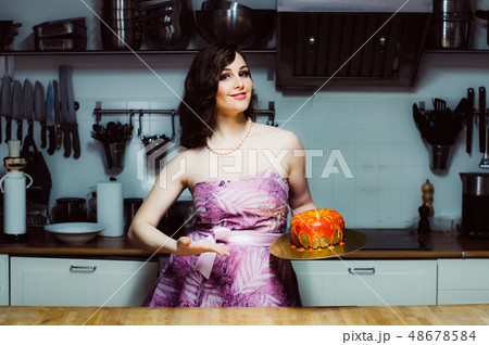 Smiling hostess holds cake like big donut with 48678584