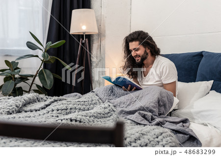 Nice joyful man sitting on the bed Nice joyful man sitting on the bed 48683299