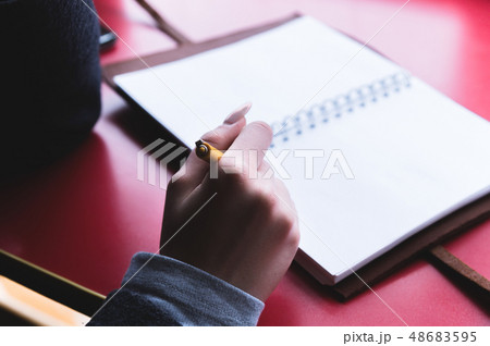 Close-up from behind the back of a young woman in a winter polto is holding a ballpoint pen and is 48683595