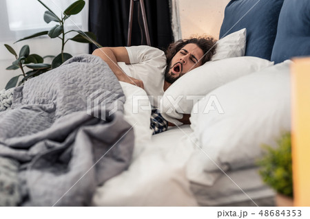 Sleepy young man yawning in the bed 48684353