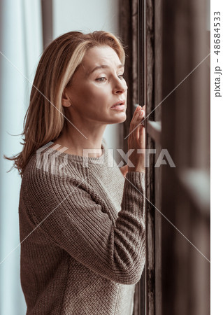 Mature woman looking into window and feeling stressed 48684533