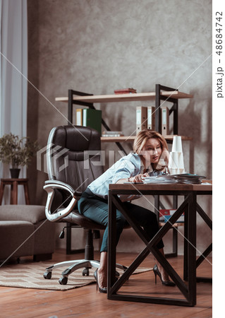 Woman wearing high heels sitting at the table feeling concerned 48684742