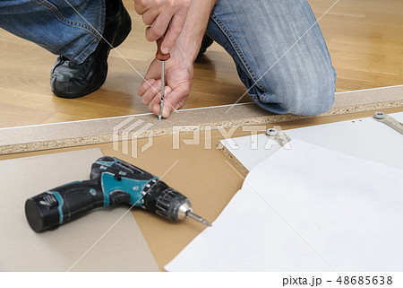 A man is assembling the furniture at home. 48685638