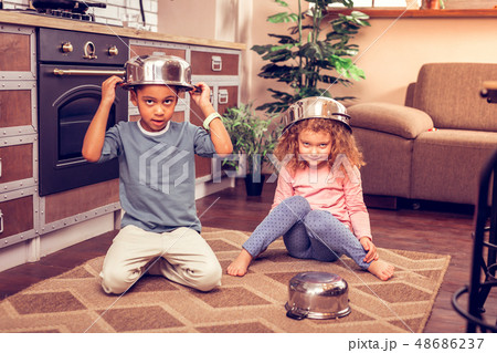 Positive delighted kids playing together with kitchenware Positive delighted kids playing together with kitchenware 48686237