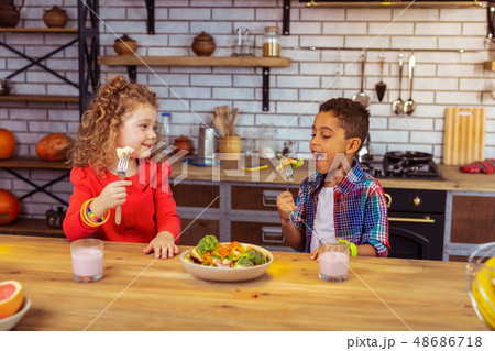 Hungry international boy eating vegetables with pleasure Hungry international boy eating vegetables with pleasure 48686718