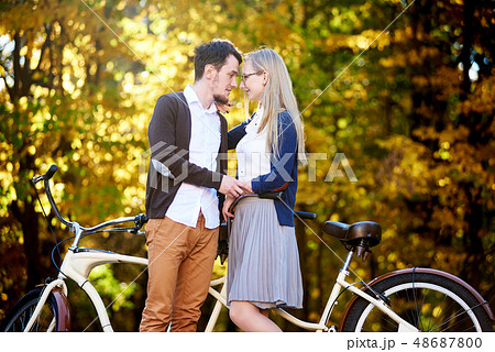 Young romantic couple bearded man and attractive woman at tandem bicycle in autumn park or forest. 48687800