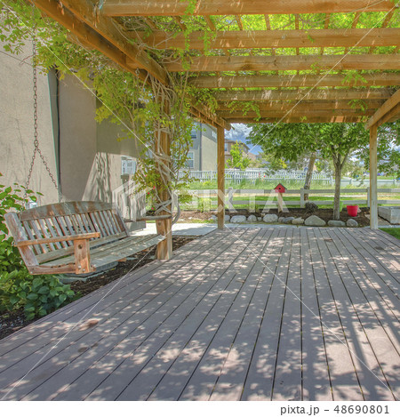 Swing hanging on a pergola covering a wooden deck Swing hanging on a pergola covering a wooden deck 48690801