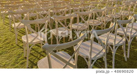 Sunlit white chairs on a bright green lawn Sunlit white chairs on a bright green lawn 48690820
