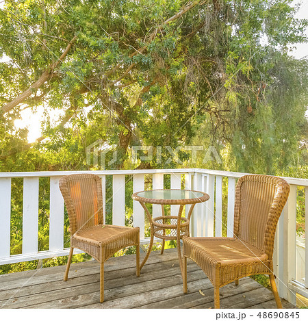 Sunlit balcony with wooven chairs and table 48690845