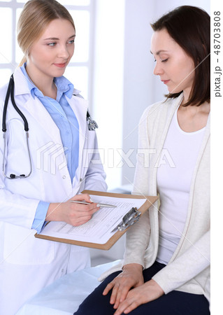 Young woman doctor and patient at medical examination at hospital office. Blue color blouse of Young woman doctor and patient at medical examination at hospital office. Blue color blouse of 48703808