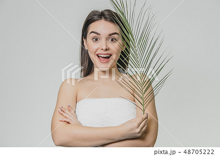 The face is a beautiful young woman with clean, perfect skin, covered with leaves. Portrait of a 48705222