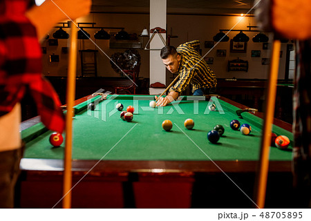 Friends plays american billiard in poolroom 48705895
