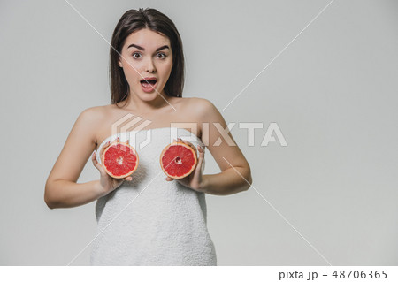 Happy young girl posing with fruit. Slices of red grapefruit in her hands on a white background Happy young girl posing with fruit. Slices of red grapefruit in her hands on a white background 48706365