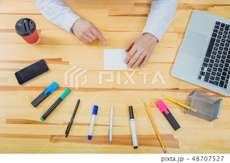 Office table with accessories: white paper, blue and pink marker, black phone, coffee cup, pen 48707527