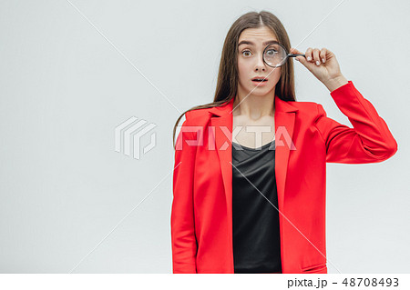 Funny expressions. Shocked woman looking at magnifying glass. A surprised girl looks at opening the 48708493