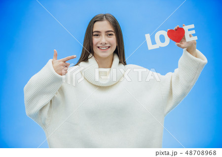 Young pretty girl dressed in white clothes. During this time it stands on a blue background. Holds a 48708968