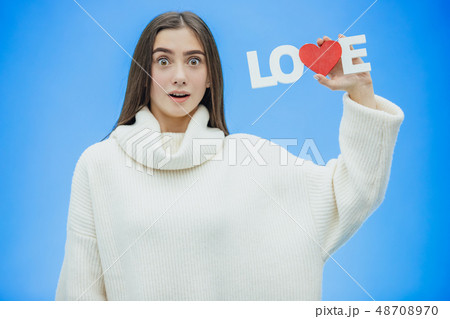 Young pretty girl dressed in white clothes. During this time it stands on a blue background. Holds a 48708970