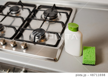 Soap in plastic bottle with sponge at gas stove. 48711698